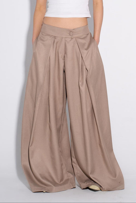 Woman wearing a white tank top and beige wide-leg pants on a white background