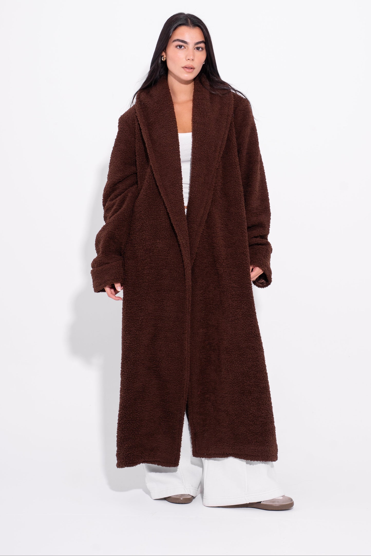 Person wearing a long brown coat on a white background